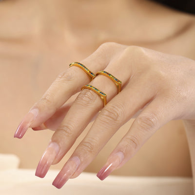 Hand wearing three gold multicolor V-shaped open band rings on fingers