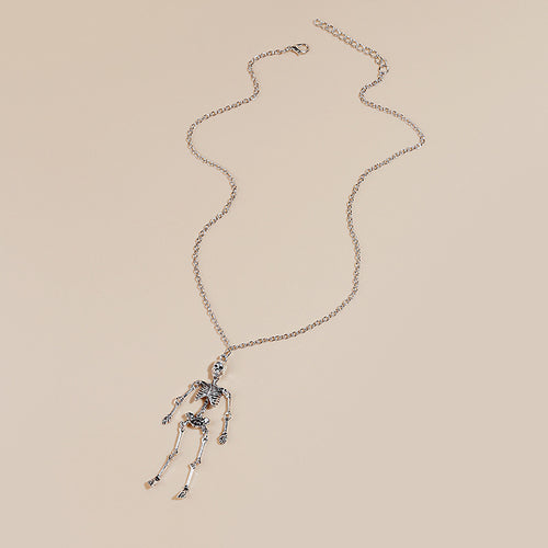 Full silver skeleton pendant necklace laid on beige background
