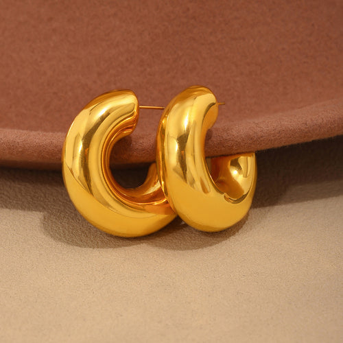 Pair of chunky gold hollow C hoops on fabric surface