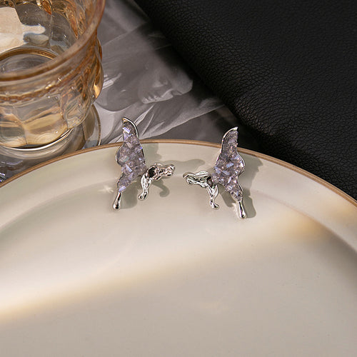 Purple crystal butterfly earrings on plate with glass props