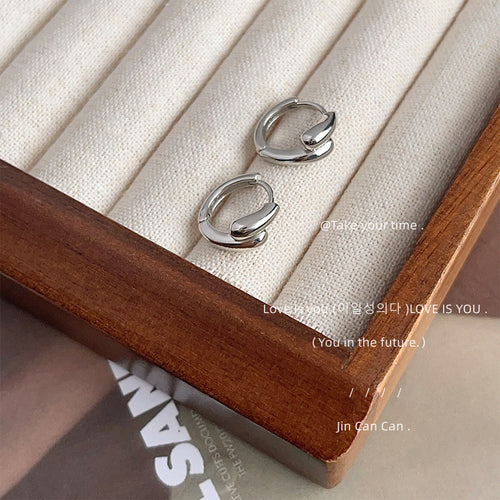 Silver-tone double-layer teardrop huggie hoops shown worn on an ear.