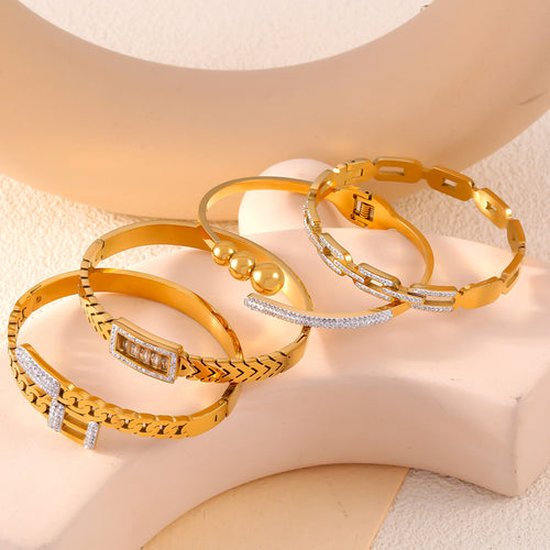 Four gold bangles arranged on beige geometric props