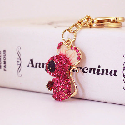 Close-up of a pink rhinestone mouse charm attached to gold-tone key rings.