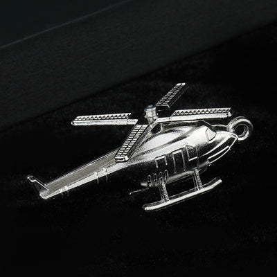 Silver-tone metal helicopter charm angled on a black velvet surface