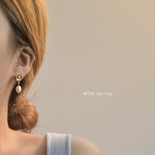 Gold daisy freshwater pearl drop earring worn on ear