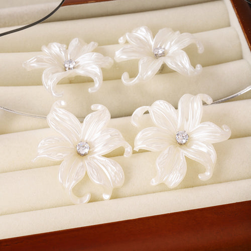 Four white pearlescent lily earrings in velvet jewelry tray
