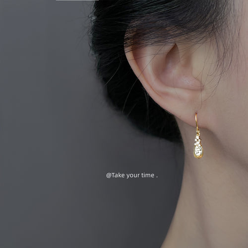 Model wearing small gold teardrop crystal hook earring