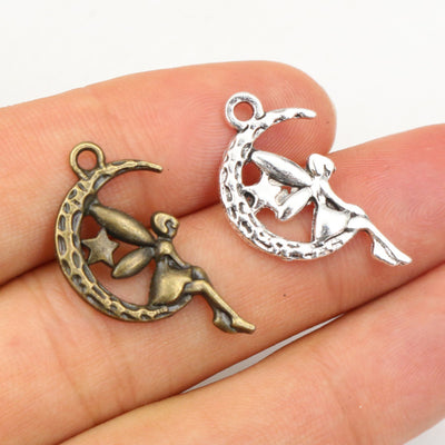 Hand held view of the moon and fairy silhouette charms showing the front shape and finish