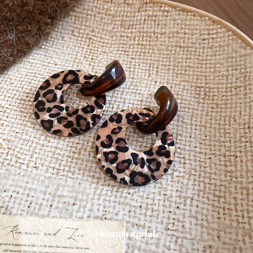 Chunky open resin hoops with two distinct brown leopard patterns shown in a styled close-up