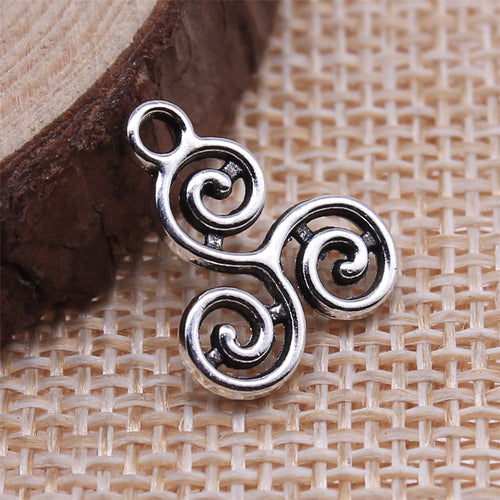 antique silver triple spiral pendant arranged on a round wood display