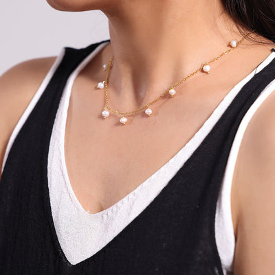 Gold freshwater pearl station necklace worn on black white top