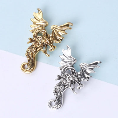 Gold and silver flying dragon brooches on dual background