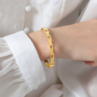 Gold geometric cutout bangle worn with white blouse sleeve