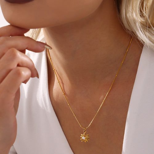 Gold sun shell-bead pendant necklace worn at collarbone with white top