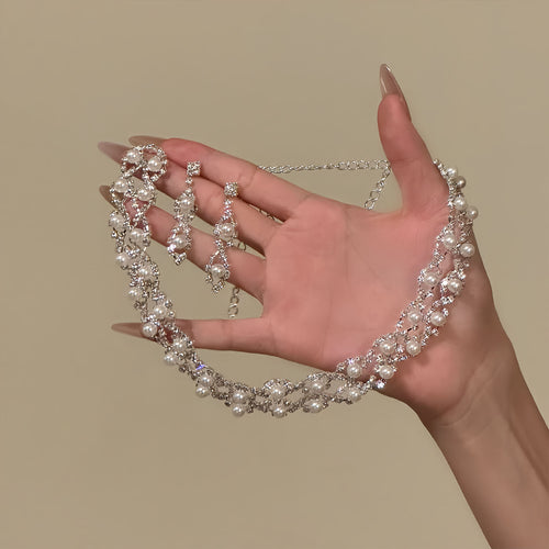 Pearl drop earrings held beside worn silver pearl choker