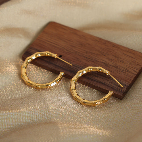 Pair of gold bamboo joint open hoops on wood block