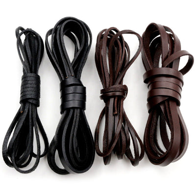 Assorted flat leather cords in black and brown arranged together on a plain background