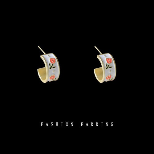 Gold white enamel tulip C hoop stud earrings on black background