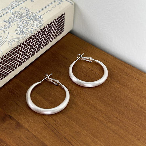 Styled close-up of plain round metal hoop earrings