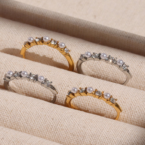 Four gold and steel shell bead zircon open rings on linen tray