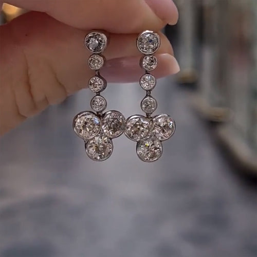Silver graduated bezel flower drop earrings front street background