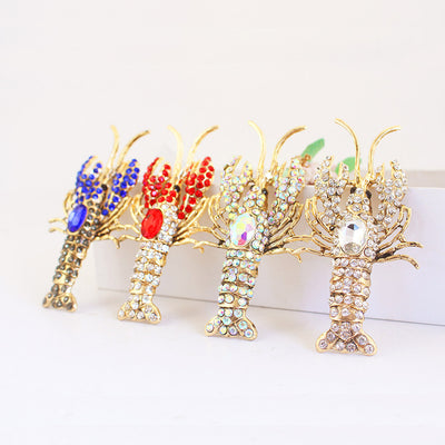Four rhinestone lobster pendants in blue, red, multicolor and white stand side by side.