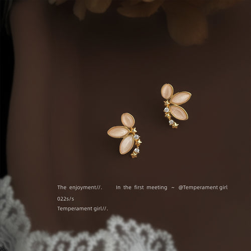 Peach cat-eye butterfly studs on model collarbone dark top