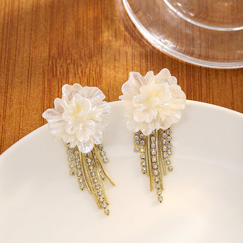 Pearl camellia gold crystal tassel earrings on white ceramic plate