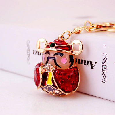 Angled close-up of a red God of Wealth keychain beside a white box.