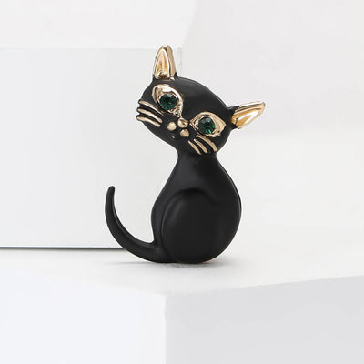 Front view showing the black enamel sitting cat brooch with green crystal eyes