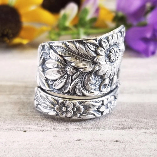 Antique silver wide floral ring side view on wood table