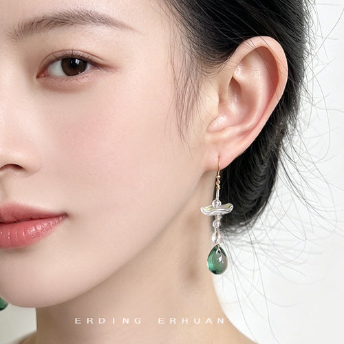 Gold-tone clear-flower green-teardrop long hooks shown worn on an ear.