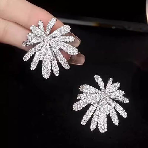 Hand holding one pave starburst earring above matching pair