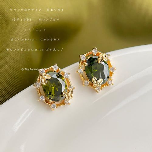 Gold olive green oval CZ butterfly frame studs on white plate