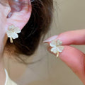 White Five-Petal Flower Stud Earrings with Polished Metal Details view 1
