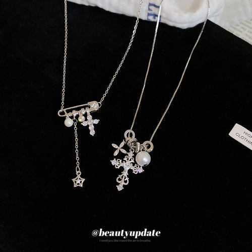 Slim silver tone chains with crystal cross, star, and pearl-like drops displayed in a close product arrangement.