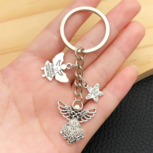 Styled close-up of antique silver guardian angel wing and star charm keychain showing colors and surface details
