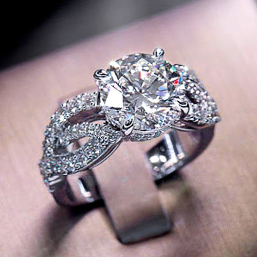 Silver round CZ twisted pave ring on metal stand close front view