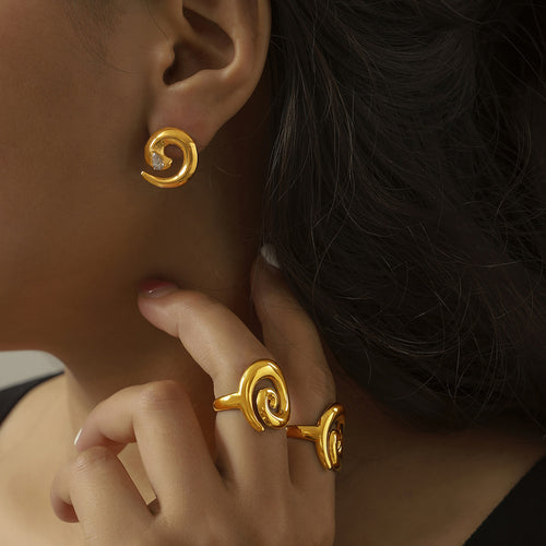 Gold spiral stud earring and swirl rings worn on hand
