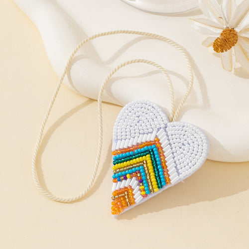 Close-up of white beaded heart pendant showing turquoise and orange chevron pattern