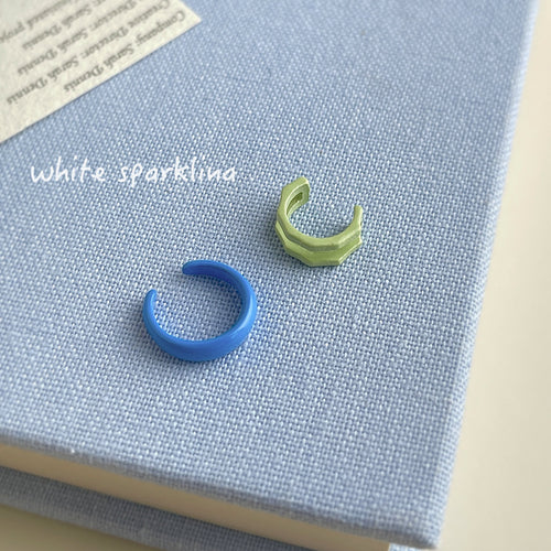 Blue C-shape and green faceted ear cuffs on blue linen