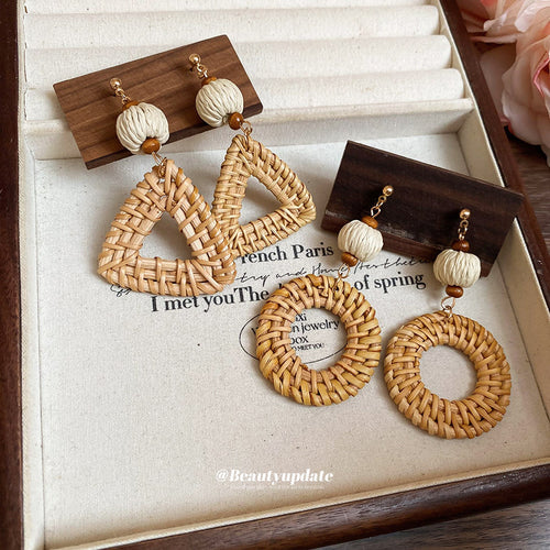 Tan woven statement drops with wood-like geometric tops displayed on a jewelry surface