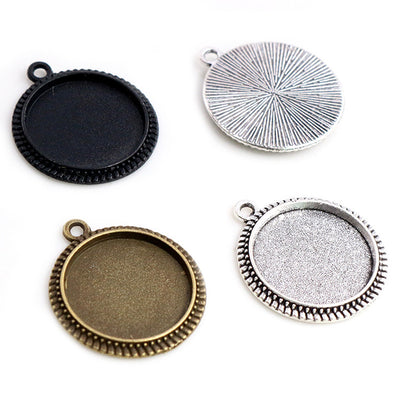 Overview of round bezel pendant trays with top loops and scalloped or beaded edge treatments arranged on a light backgro