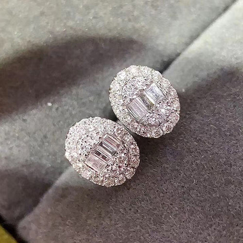 Close-up of oval double pavé halo studs with center baguettes on gray surface