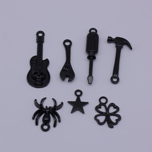 Black Tool and Symbol Charms in Seven Designs for Jewelry Making held in hand for scale