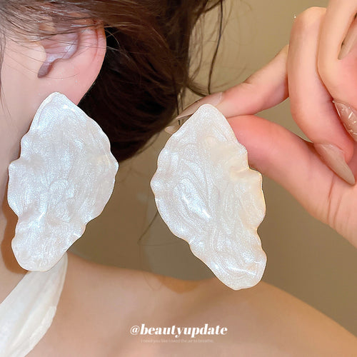 Large irregular leaf silhouettes with a rippled pearly white surface shown in a styled front view.