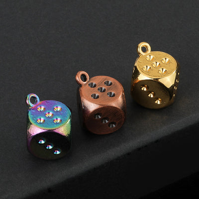 Three dice charms in rainbow, antique copper and gold-tone finishes on a dark background