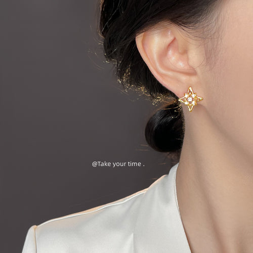 Gold starburst stud earring worn on ear side profile