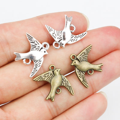 Grouped front view of flying bird metal charms in antique bronze and silver tones