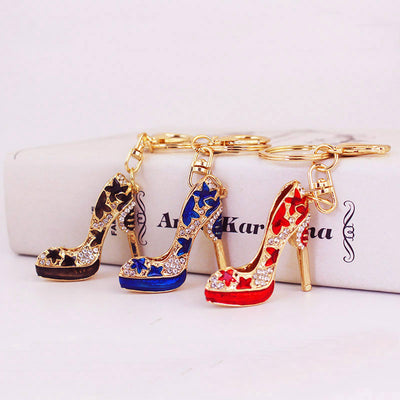 Three gold-tone high heel shoe keychains in black, blue, and red stand side by side.